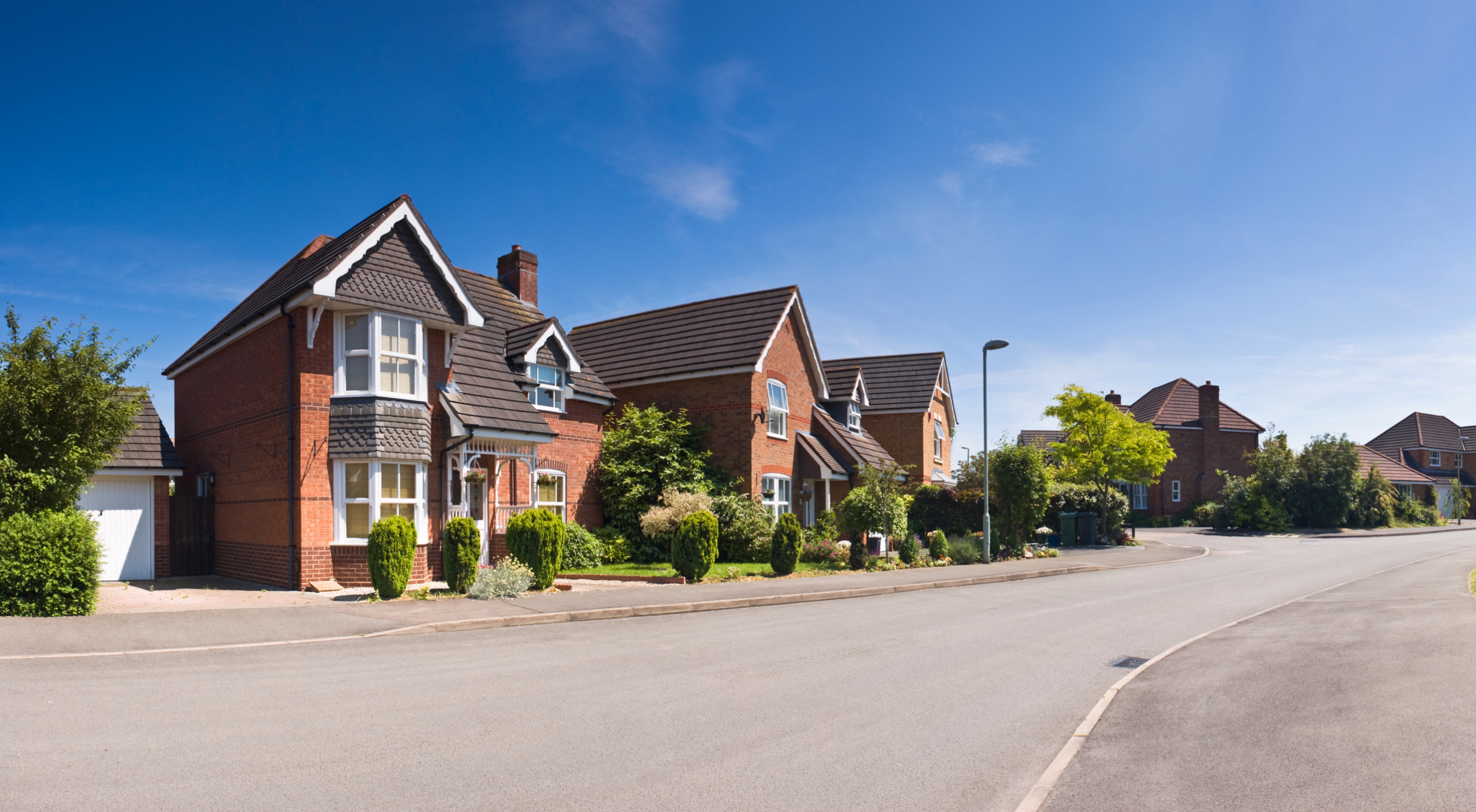 Red brick suburban house under blue sky