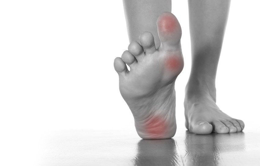 A grayscale image of a person's bare foot stepping forward, with the heel and ball highlighted in red to indicate pain or discomfort on the sole