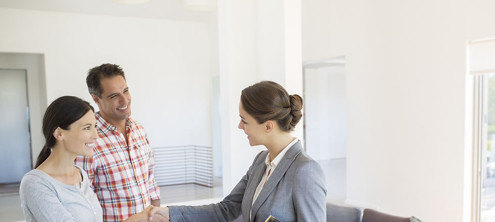 Female estate agent smiling while shaking hands with a new client in a living room