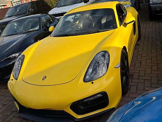 Front three quarter view of a bright yellow Porsche sports car showing its front windscreen