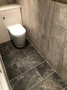 Modern toilet install featuring dark grey slate floor tiles and textured stone wall panels