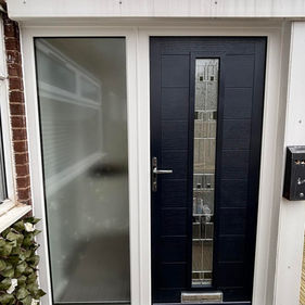 A modern entrance features a black door with vertical glass panels