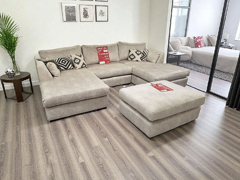 A cozy living room featuring a comfortable couch and a matching ottoman, with warm lighting and decorative pillows