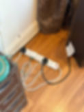 Four-way extension lead with plugs plugged into it resting on a wooden floor