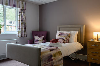 A cozy bedroom with a single bed featuring colorful abstract bedding and matching cushions