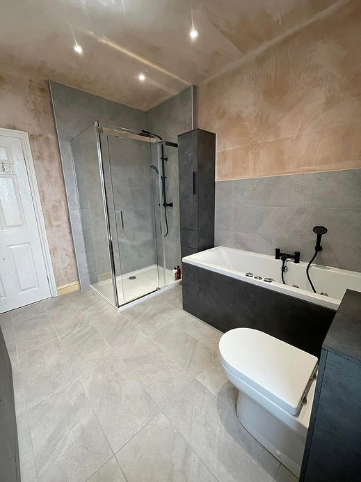 A bathroom featuring a shower, toilet, and sink, with neutral-colored tiles and modern fixtures