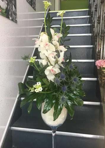 Tall white gladioli arrangement in a white vase on stairs