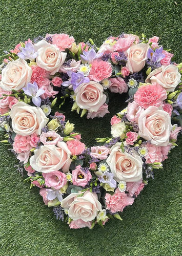 Heart-shaped floral tribute with light pink roses and purple accents
