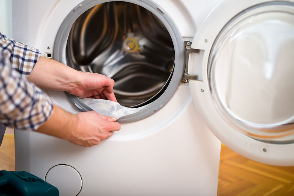 A man placing a cloth into the front of a washing machine for laundry