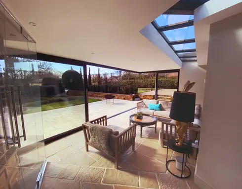 Sunroom seating area with flagstone tiles and floor to ceiling glass walls
