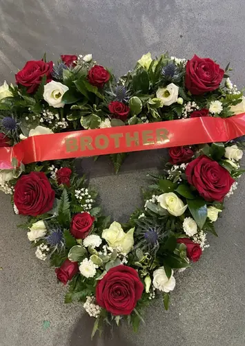 Heart-shaped wreath with red roses and a red ribbon