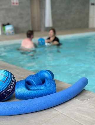 Poolside view with a blue foam noodle, dumbbell, and ball on the deck