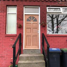 Red brick house exterior with beige door marked "22" and small transom window