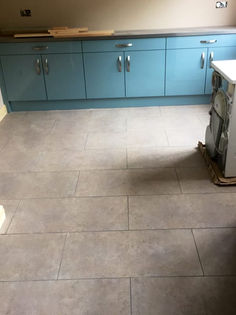 Kitchen renovation showing newly laid grey slate floor tiles and blue lower cabinets
