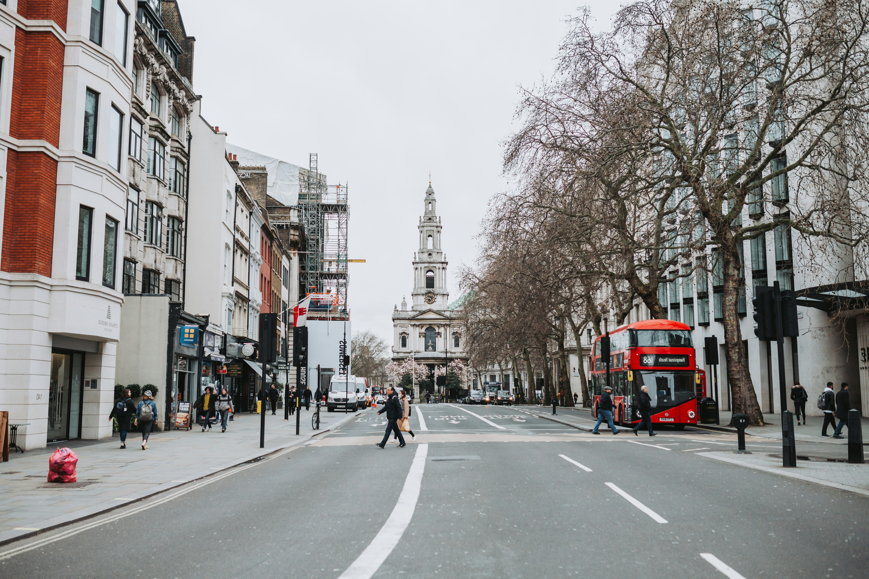 London street with a red double-decker bus and a church in the background