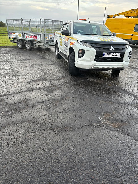 White pickup truck with a trailer parked on wet asphalt