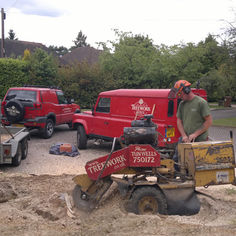 Treework company worker operating a yellow stump grinder in a driveway