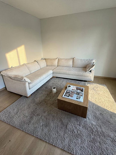 A white couch in a cozy room, accompanied by a table and a coffee table, creating a welcoming living space