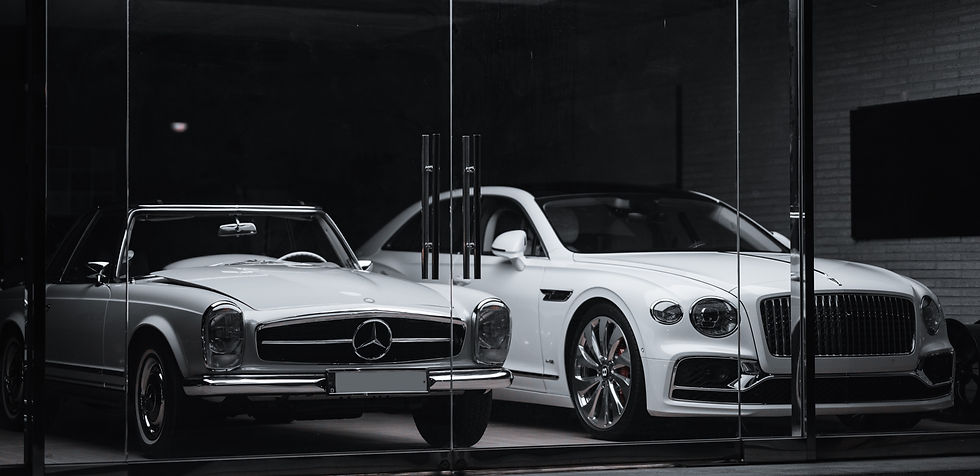 Two sleek white luxury cars, a classic convertible and a modern sedan, are parked side by side
