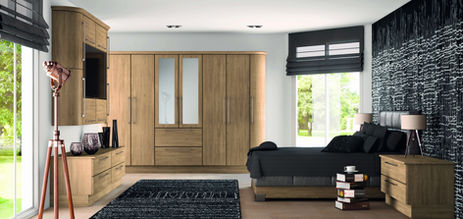 Modern bedroom with light oak wardrobes and a black feature wall