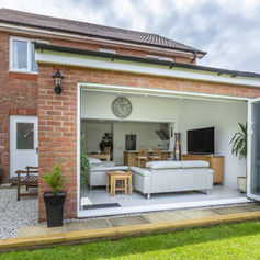 Spacious conservatory with skylights, wicker seating, glass coffee table, and garden view through large windows and door