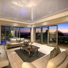 A cozy living room featuring large windows showcasing a vibrant sunset over the horizon