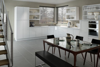 Modern white kitchen with a dark dining table and bench