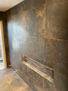 Feature wall lined with large format metallic rust effect porcelain tiles and an integrated shelf alcove
