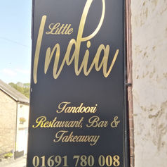 Vertical black illuminated sign for a restaurant named "Taste of India".
