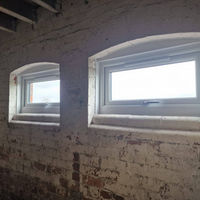 Two windows framed in a room with exposed brick walls, allowing natural light to illuminate the space