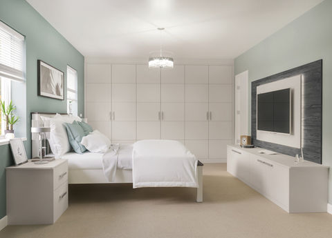 Bright modern bedroom with white fitted wardrobes and a matching TV unit