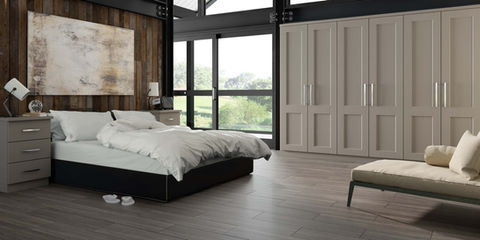 Modern bedroom with grey fitted wardrobes and a white lounge chair