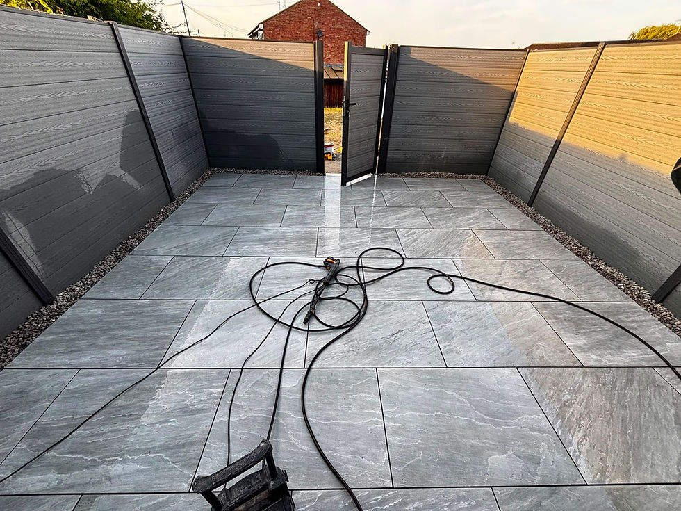 Newly installed grey patio with composite fencing and open gate