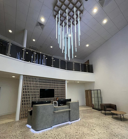 Modern office reception lobby featuring a dramatic long vertical hanging LED light installation