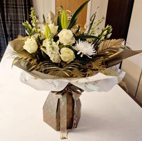 An elegant bouquet featuring white roses, lilies, and chrysanthemums with gold-toned foliage