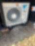 A small air conditioner unit positioned outside a residential home, providing cooling for the interior