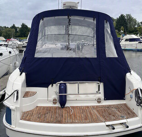 Rear view of a fitted navy blue marine canvas enclosure on a boat moored at a harbor