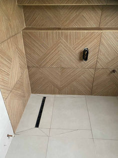 Walk in shower enclosure with modern textured beige wall tiling and a linear drainage channel