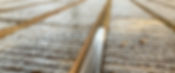 Close-up of a wet wooden deck with parallel grooves, glistening in daylight
