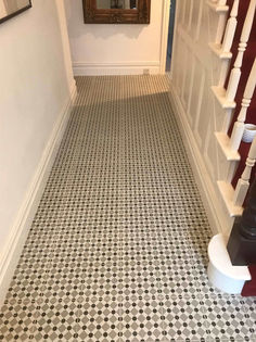 Residential hallway showing a staircase next to intricate black and white mosaic floor tiles