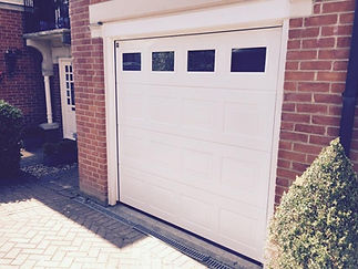 A white garage door featuring a rectangular window at the top center