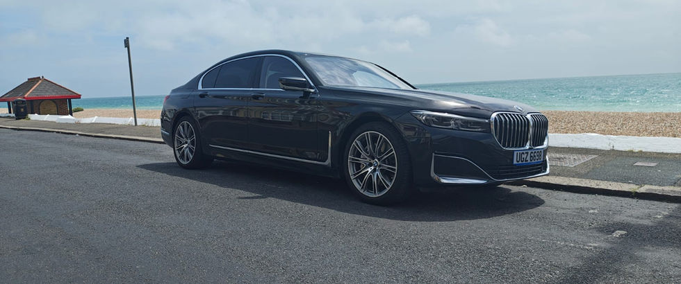 Black BMW sedan parked on a coastal road overlooking the ocean