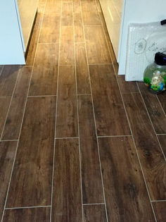 Domestic hallway featuring dark wood effect porcelain floor tiling laid in a staggered pattern