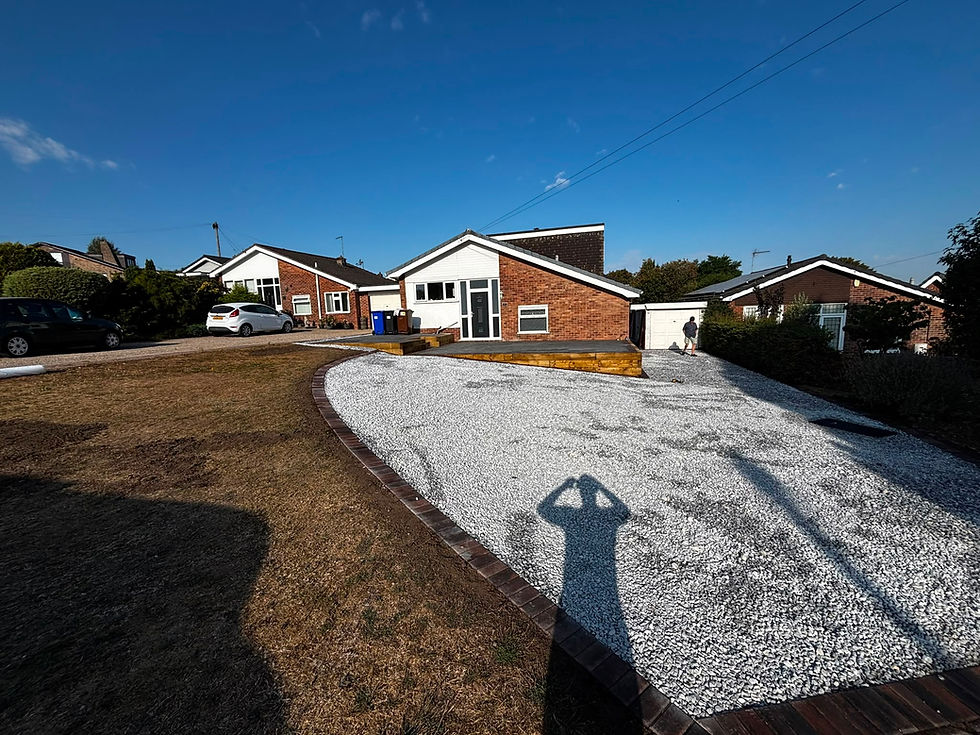 New gravel driveway in front of a brick bungalow on a sunny day