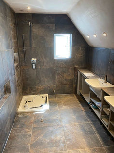 Under construction wet room bathroom with slate floor tiles and sloping loft ceiling