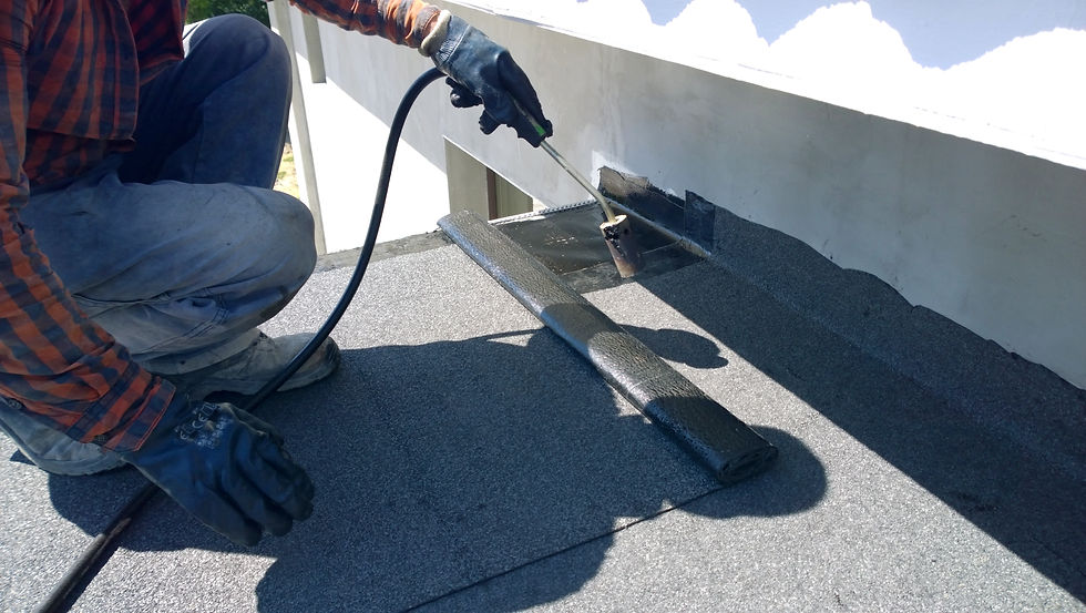 Roofer using a gas torch to apply felt waterproofing layer to a flat roof structure