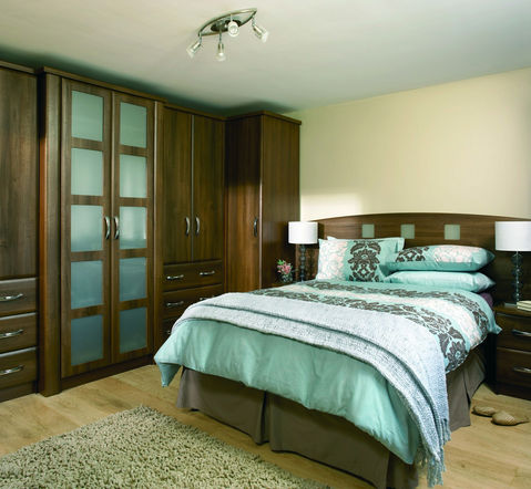 Dark wood fitted wardrobes in a cozy bedroom with striped bedding