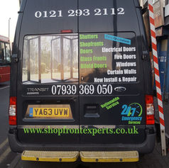 Black van rear doors covered with vibrant multi-colored advertising text, phone numbers, and services.