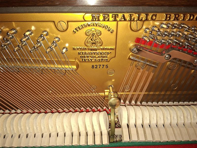 Close-up of a piano's inner mechanics showing strings, hammers, and a metal plate