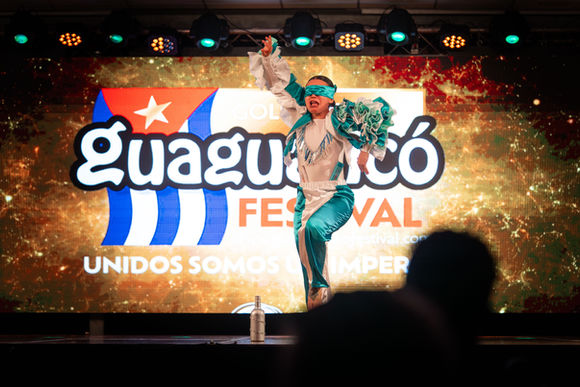 Festival Guaguancó performer dancing on stage, background banner. Unidos Somos Imperios.